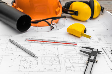 Construction plans with helmet and drawing tools on blueprints