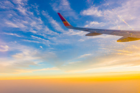 Wing of an airplane flying above the clouds at sunset