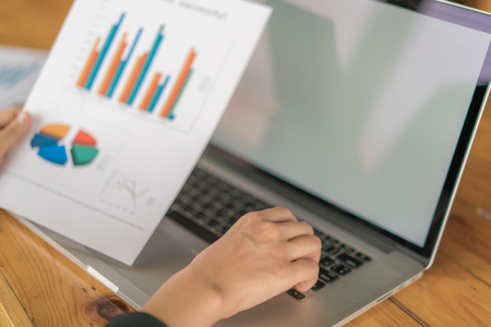 Business woman hand with Financial charts and laptop on the tableの写真素材