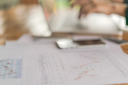 Business woman hand with Financial charts and laptop on the tableの写真素材