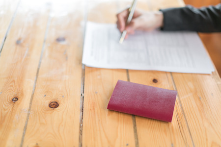 Hand with pen over  Travel Aviation Insurance application form and passportの写真素材