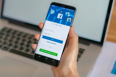Loei, Thailand - May 10, 2017: Hand holding samsung s8 with mobile application for Facebook on the screenのeditorial素材