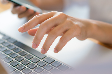 Business woman hand with Financial charts and mobile phone over laptop on the tableの写真素材
