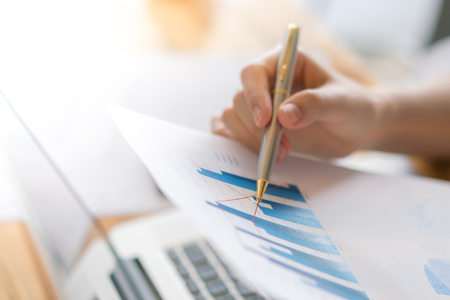 Business woman hand with Financial charts and laptop on the tableの写真素材