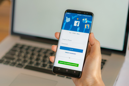 Loei, Thailand - May 10, 2017: Hand holding samsung s8 with mobile application for Facebook on the screenのeditorial素材