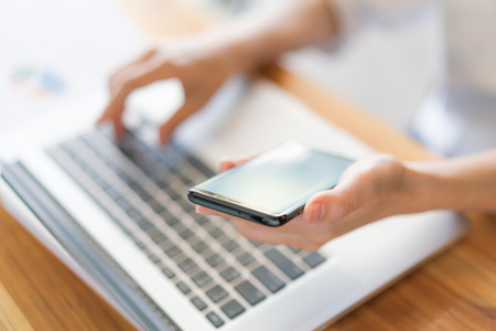 Business woman hand with Financial charts and mobile phone over laptop on the tableの写真素材