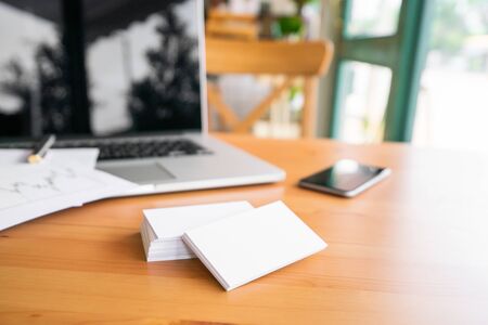 Blank business cards and laptop on wooden surface.の写真素材
