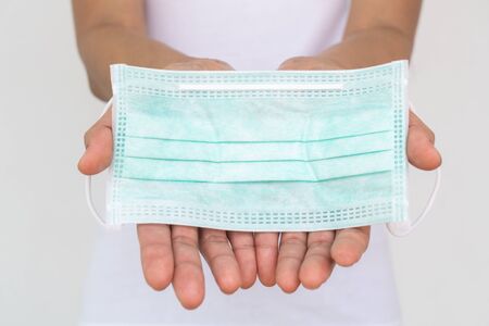 A woman holding a face mask. Surgical mask protects against the spread of Coronavirus (COVID-19). Medical mask. Face mask. Surgical mask.の写真素材