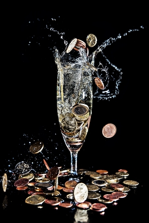 Coins falling into a champagne glassの写真素材