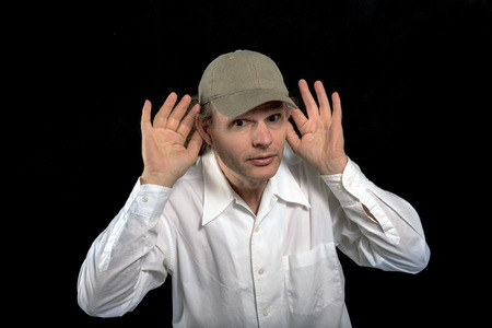 Man listening with his hands to his ears on a black backgroundの写真素材