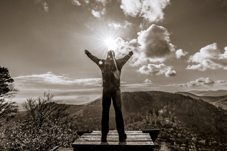 Man stands on the mountain and reaches for the sun