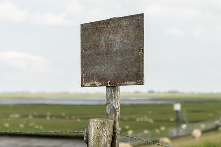 Wooden sign on a post with copy space in front of a North German coastal landscapeの写真素材