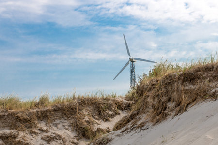 German Baltic Sea coast with wind turbine, sand dunes, grass,and blue sky