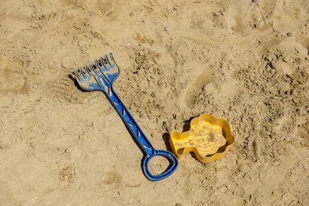 Children's toys, shovel and sand mold lie on light sandの写真素材