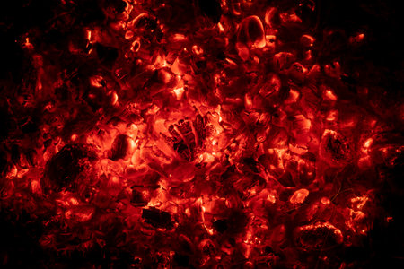 Red glowing charcoal in a campfire against a black background
