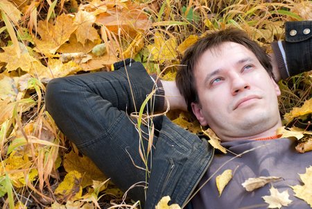 a man lying on autumn leavesの写真素材