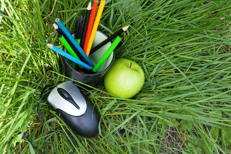 computer mouse, apple and pencils in a glass, on the grassの写真素材