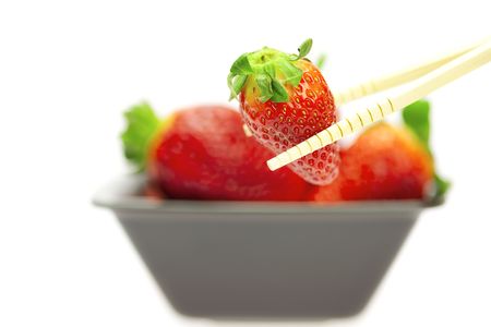 juicy strawberries in a bowl and Chinese chopsticks isolated on whiteの写真素材