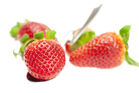 juicy strawberries on spoon isolated on whiteの写真素材