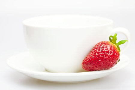 juicy strawberries and a cup of white isolated on whiteの写真素材