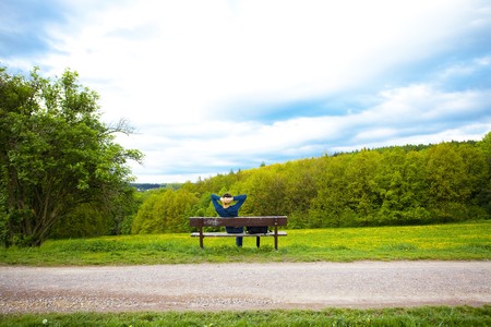 male resting on the bench on the field of dandelionsの写真素材