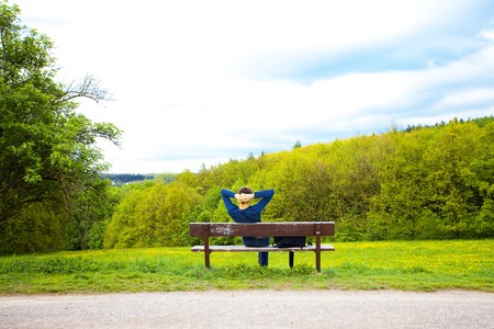 male resting on the bench on the field of dandelionsの写真素材