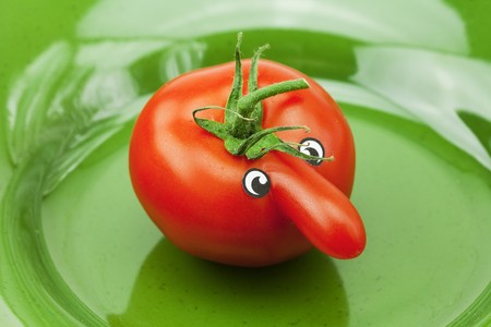 tomato with a nose lying on the green dishの写真素材