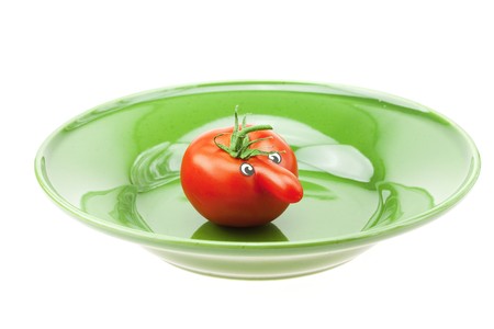 tomato with a nose on the plate and the green isolated on whiteの写真素材
