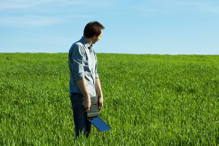 young man using laptop in the fieldの写真素材