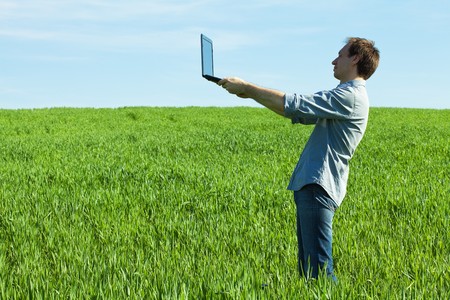 young man using laptop in the fieldの写真素材