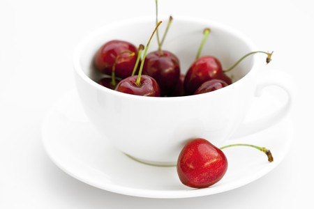cup saucer and cherries isolated on whiteの写真素材