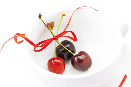 cherry with ribbon in the cup isolated on a whiteの写真素材