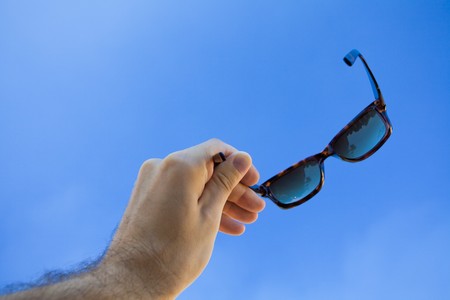 Glasses  in the hands against the skyの写真素材