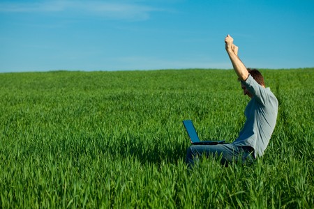 young man using laptop in the fieldの写真素材