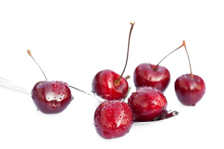 cherries with drops of water in the spoon isolated on whiteの写真素材