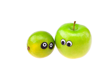 lime and apple with eyes and faces isolated on whiteの写真素材