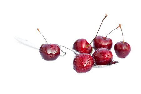 cherries lying in the spoon isolated on whiteの写真素材