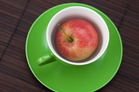 cup, saucer and apples on a bamboo matの写真素材
