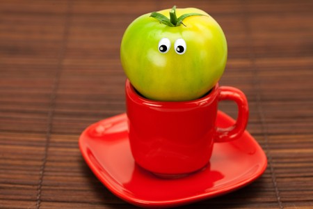 tomato with eyes in the cup on a bamboo matの写真素材