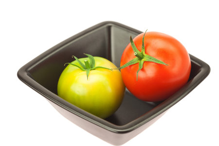 green and red tomatoes in a bowl isolated on whiteの写真素材