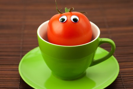 tomato with eyes in the cup on a bamboo matの写真素材