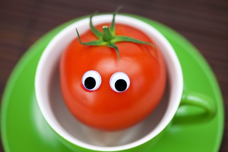 tomato with eyes in the cup on a bamboo matの写真素材