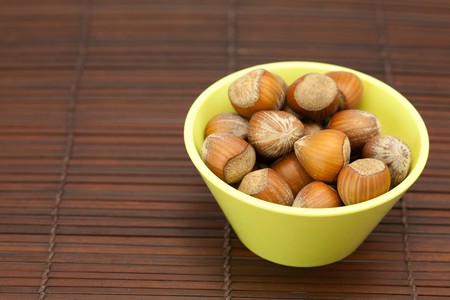 hazelnuts in a bowl on a bamboo matの写真素材