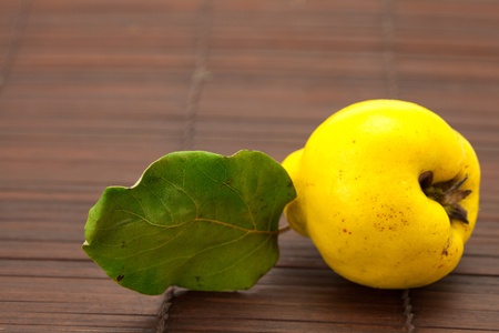 yellow quinces with a green leaf on a bamboo matの写真素材