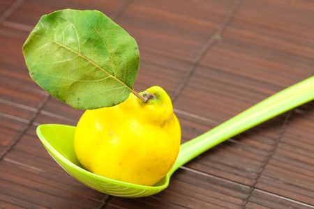 yellow quinces with a green leaf in a spoon on a bamboo matの写真素材