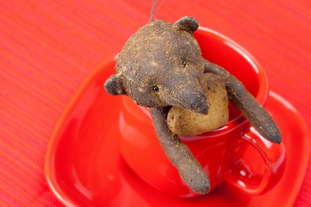 teddy bear  handmade and cookie  in the form of heart  in a cup  on a red backgroundの写真素材