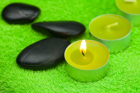 burning candle and spa black stones lying on the towelの写真素材