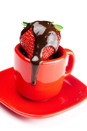 strawberries in chocolate lying in a red cup isolated on whiteの写真素材