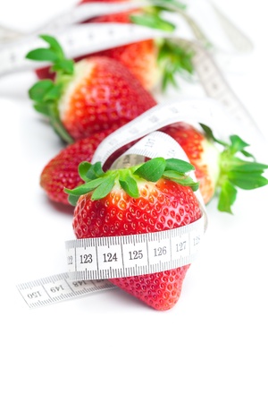 big juicy red ripe strawberries and measure tape isolated on whiteの写真素材