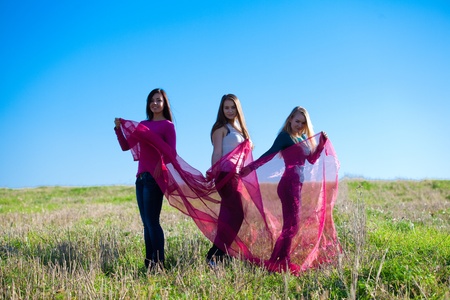 three young beautiful woman standing with tissue into the field against the skyの写真素材
